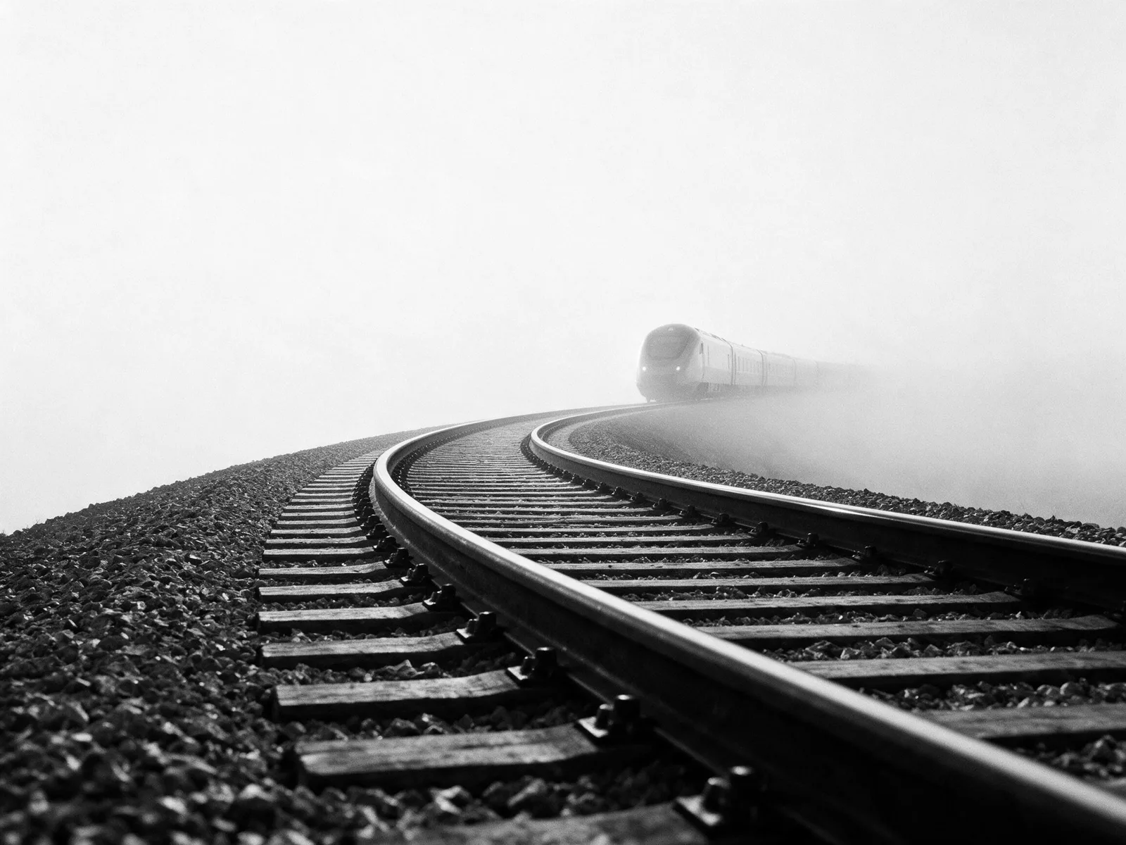 A railway track curving away into the distance, photographed in black and white.